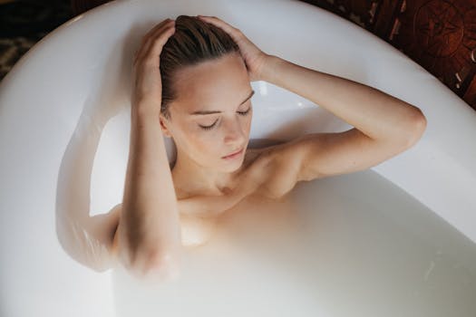 Woman relaxing in a milk bath with eyes closed and hands on head, promoting calmness and spa luxury.